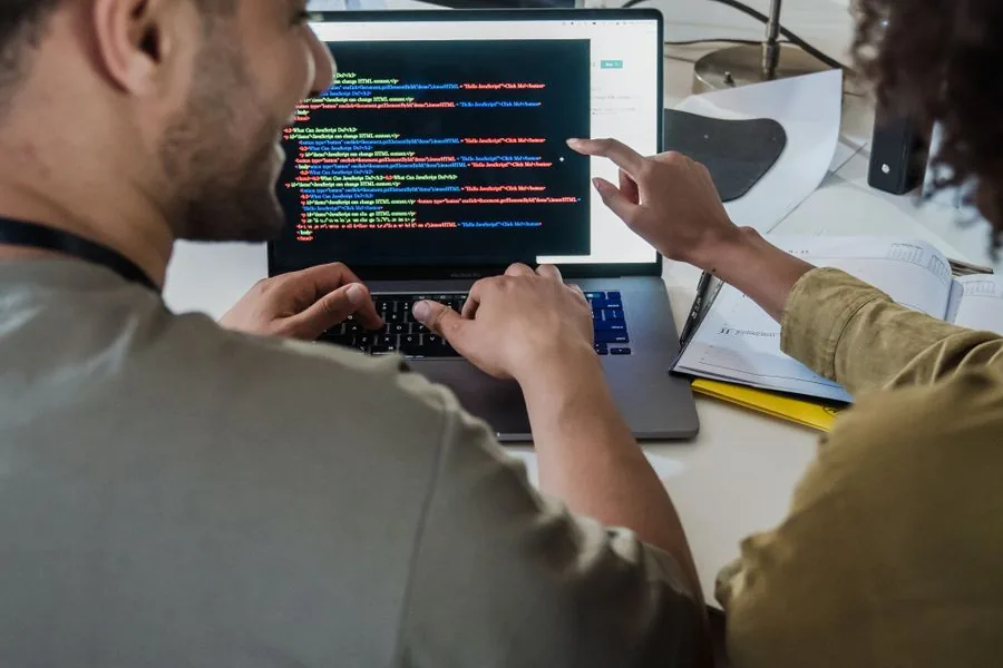 Two colleagues reviewing product documentation on a laptop together