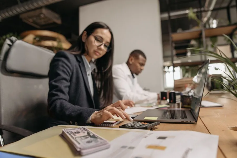 An accountant reviewing figures with a calculator and laptop